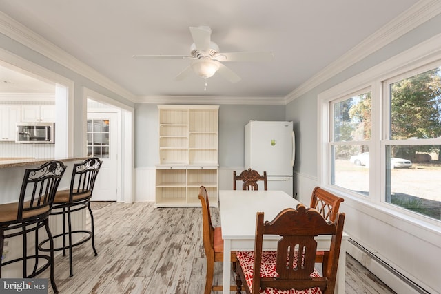 dining room featuring ornamental molding, light wood-type flooring, ceiling fan, and a baseboard heating unit