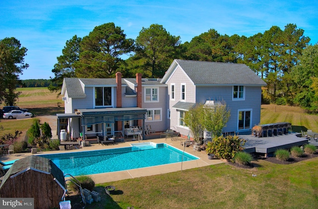 rear view of property featuring a yard, a pergola, and a pool side deck