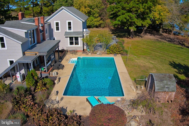 view of pool featuring a patio area, a yard, and a shed