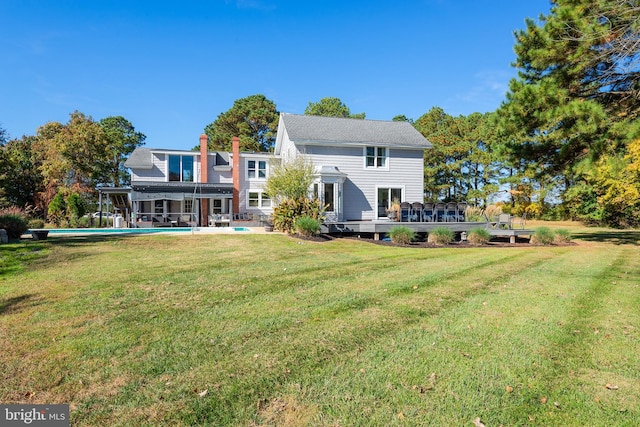 rear view of property with a lawn and a pool side deck