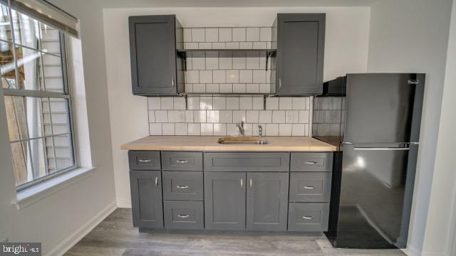 kitchen featuring gray cabinets, stainless steel refrigerator, and plenty of natural light