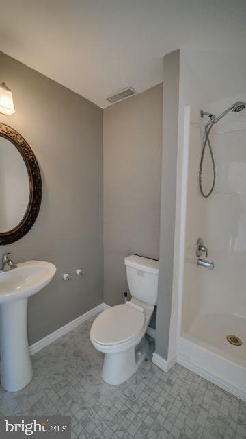 bathroom featuring a shower, sink, and toilet