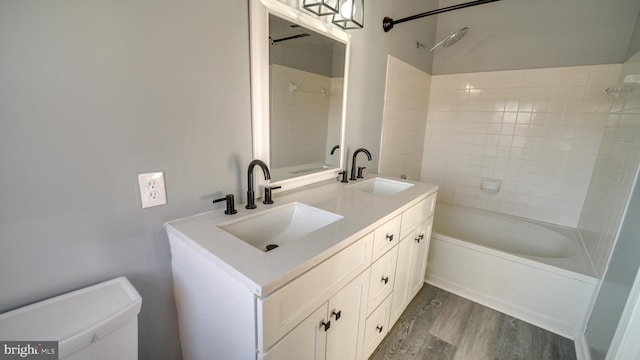 full bathroom with hardwood / wood-style floors, vanity, toilet, and tiled shower / bath