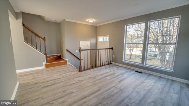 interior space with light hardwood / wood-style floors and ornamental molding