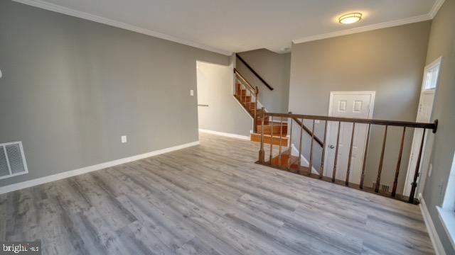 spare room featuring crown molding and light hardwood / wood-style flooring