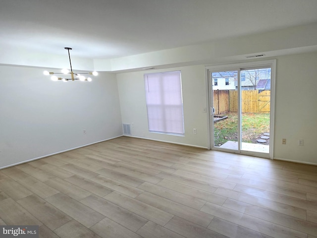 unfurnished room with light hardwood / wood-style floors and a chandelier