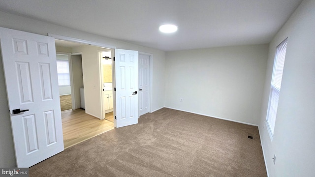 unfurnished bedroom featuring light carpet and multiple windows