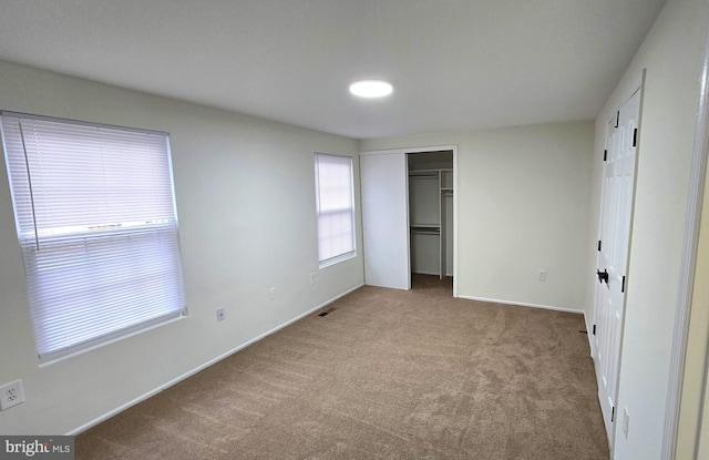 unfurnished bedroom with light carpet and a closet