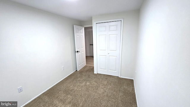 unfurnished bedroom with dark colored carpet and a closet