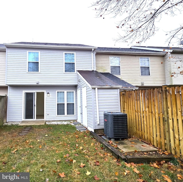 rear view of property featuring a lawn and central air condition unit