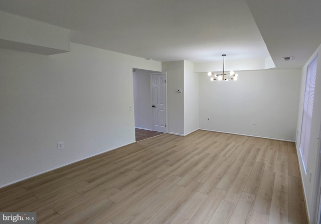 empty room featuring a chandelier and light hardwood / wood-style flooring