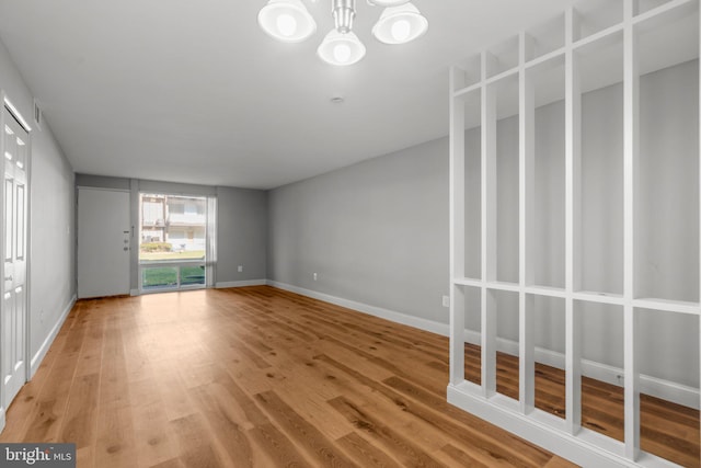 unfurnished room featuring wood-type flooring and an inviting chandelier