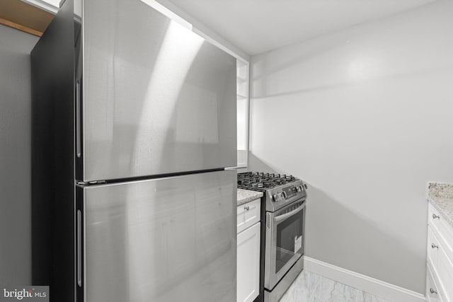 kitchen featuring white cabinets, stainless steel appliances, and light stone countertops