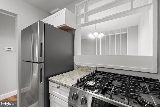 kitchen with stainless steel appliances, an inviting chandelier, light stone counters, hardwood / wood-style floors, and white cabinets