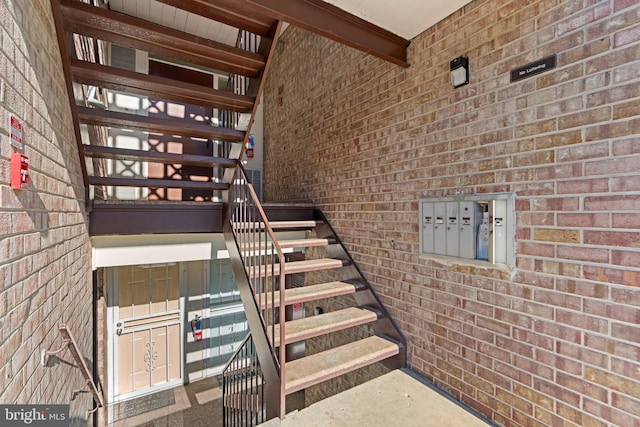 stairway with a mail area and brick wall