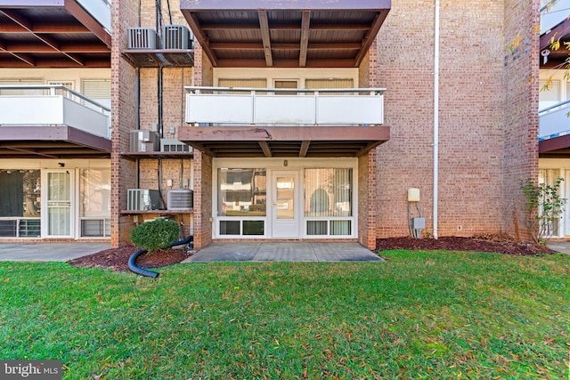 rear view of house with a patio, a balcony, and a lawn