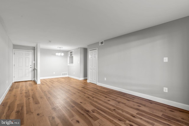 unfurnished room with hardwood / wood-style flooring and an inviting chandelier