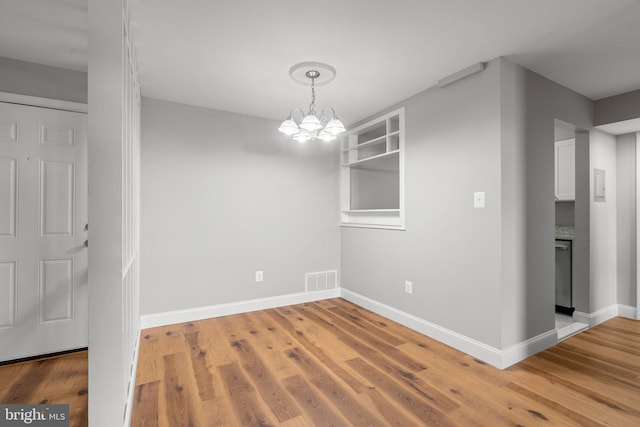 unfurnished dining area featuring hardwood / wood-style floors and an inviting chandelier