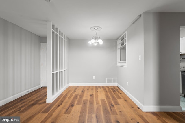 unfurnished dining area with hardwood / wood-style floors and a notable chandelier