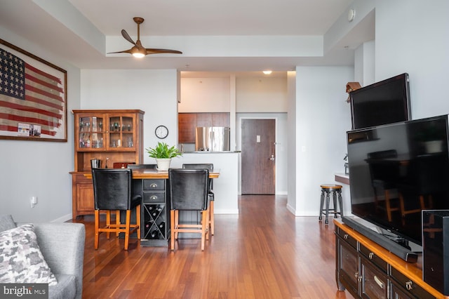 dining area with hardwood / wood-style floors, a tray ceiling, and ceiling fan