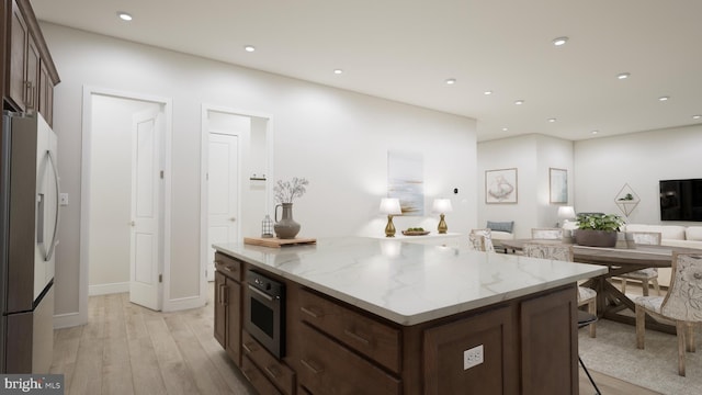 kitchen featuring a breakfast bar, light hardwood / wood-style flooring, light stone countertops, a kitchen island, and stainless steel appliances