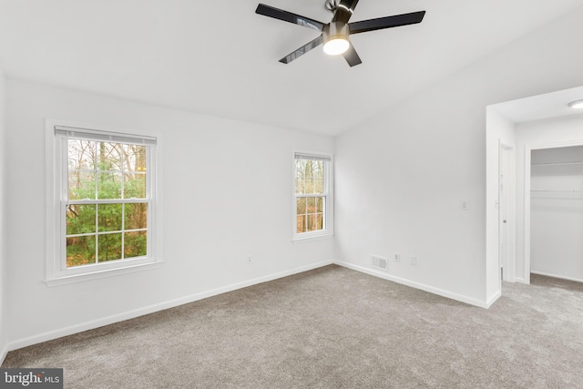 carpeted spare room featuring lofted ceiling, ceiling fan, and a healthy amount of sunlight