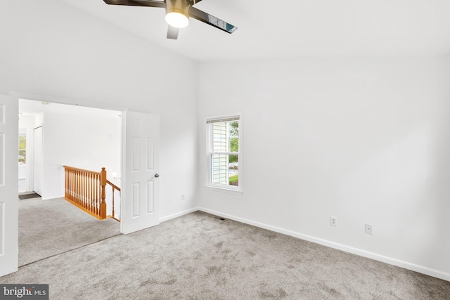 carpeted spare room with ceiling fan and high vaulted ceiling