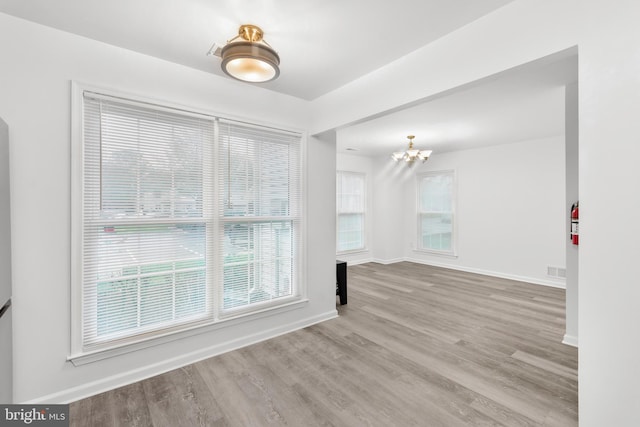 spare room featuring an inviting chandelier and light wood-type flooring