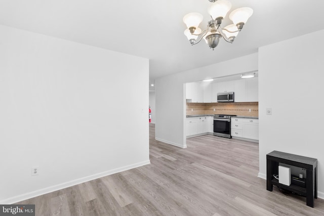 unfurnished living room featuring a chandelier and light hardwood / wood-style flooring