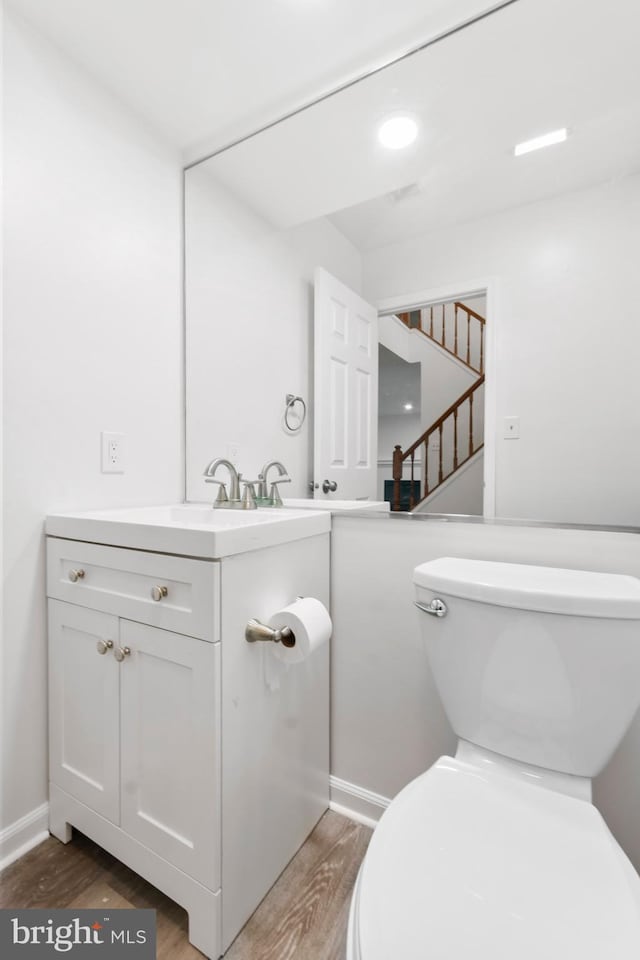 bathroom featuring toilet, vanity, and hardwood / wood-style flooring