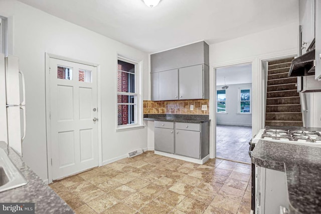 kitchen featuring tasteful backsplash, white appliances, sink, gray cabinets, and range hood