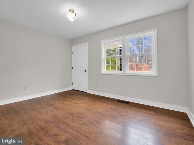 unfurnished room with a textured ceiling and dark wood-type flooring