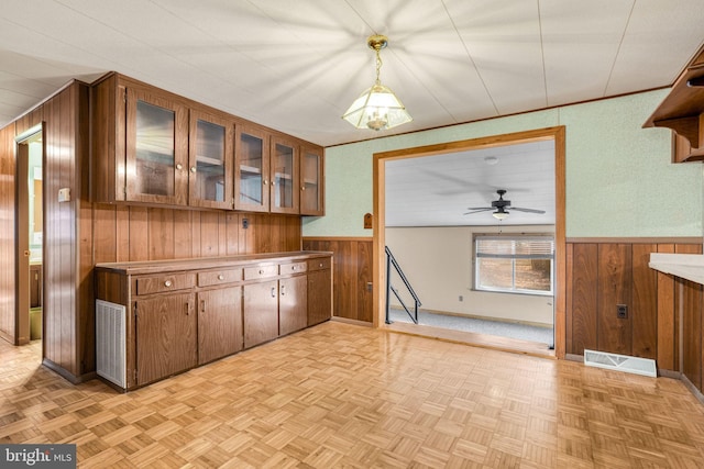 kitchen with pendant lighting, light parquet flooring, and wooden walls