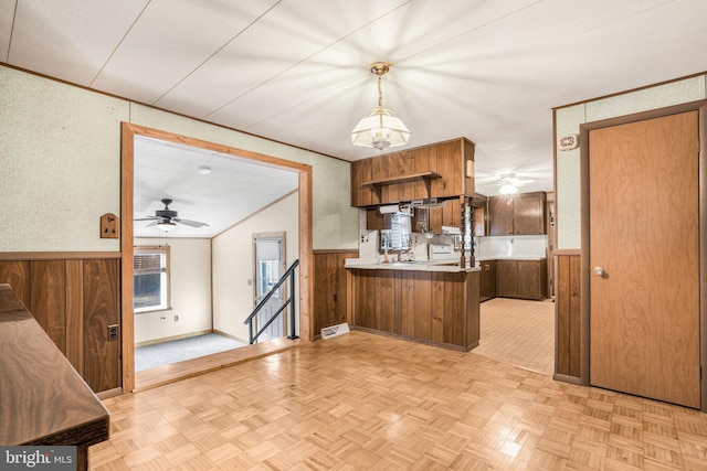 kitchen featuring ceiling fan, kitchen peninsula, light parquet floors, decorative light fixtures, and wooden walls