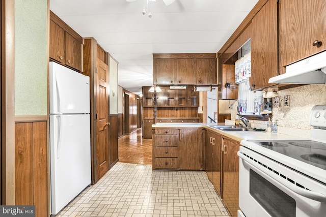 kitchen with wood walls, white appliances, ventilation hood, sink, and decorative backsplash