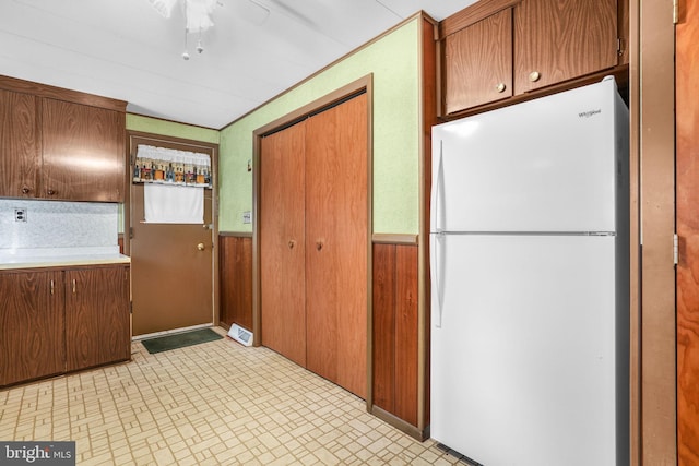 kitchen with wood walls, ceiling fan, and white refrigerator