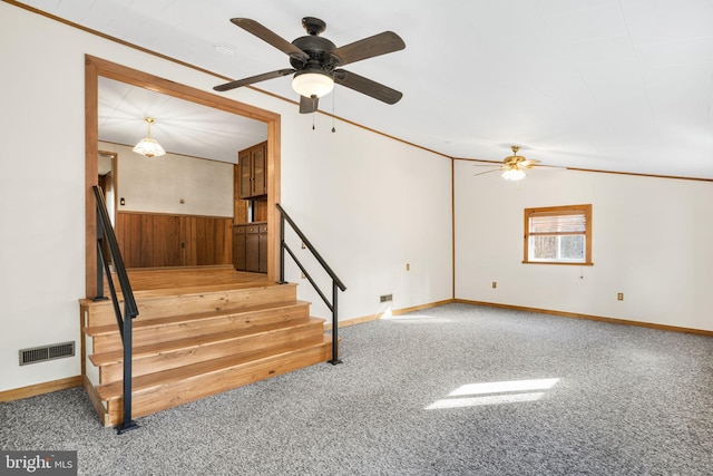 stairway featuring wood walls, crown molding, carpet floors, and ceiling fan