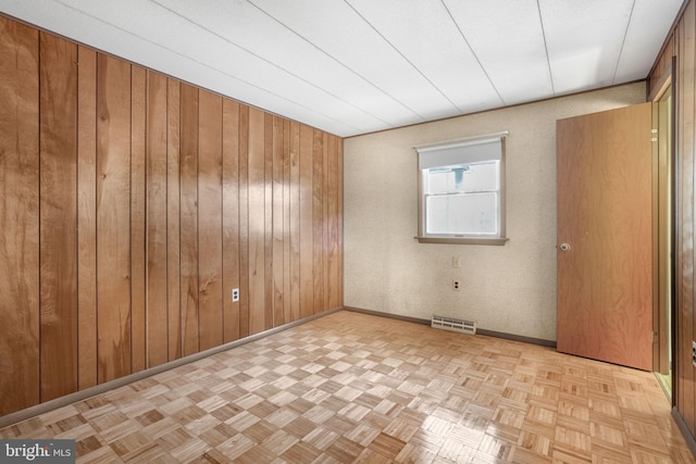 empty room with wooden walls and light parquet flooring