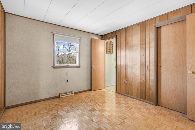 unfurnished bedroom with light parquet flooring and wood walls