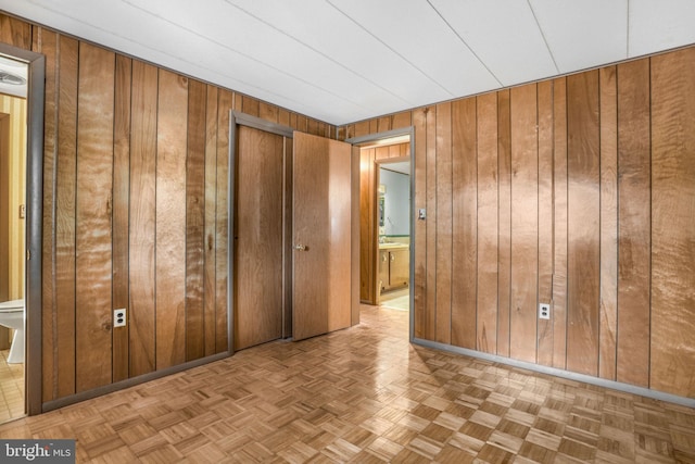 unfurnished bedroom with light parquet floors and wood walls