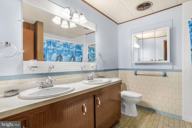 bathroom featuring toilet, vanity, tile patterned floors, and tile walls