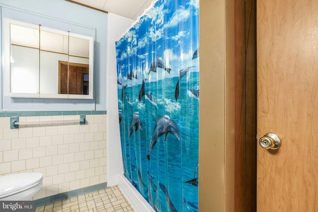 bathroom featuring tile patterned flooring, tile walls, and toilet