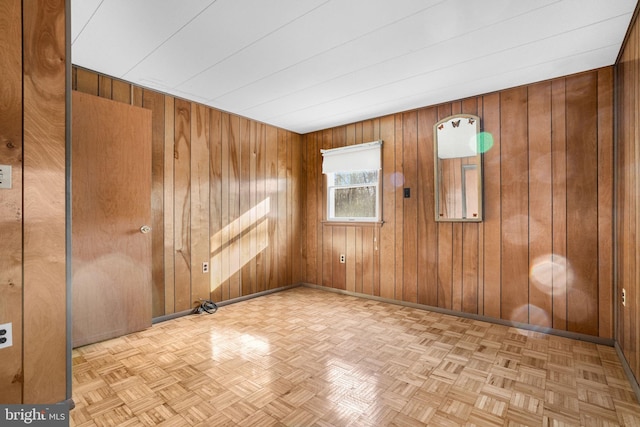 unfurnished room with light parquet floors and wooden walls