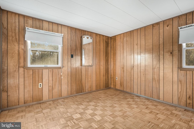 spare room with light parquet floors and wooden walls