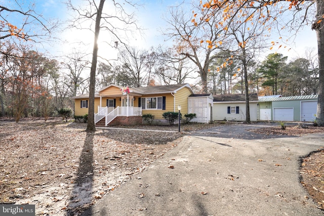 ranch-style home with covered porch, an outdoor structure, and a garage