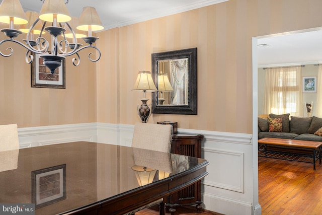 dining area with hardwood / wood-style floors, a notable chandelier, and ornamental molding