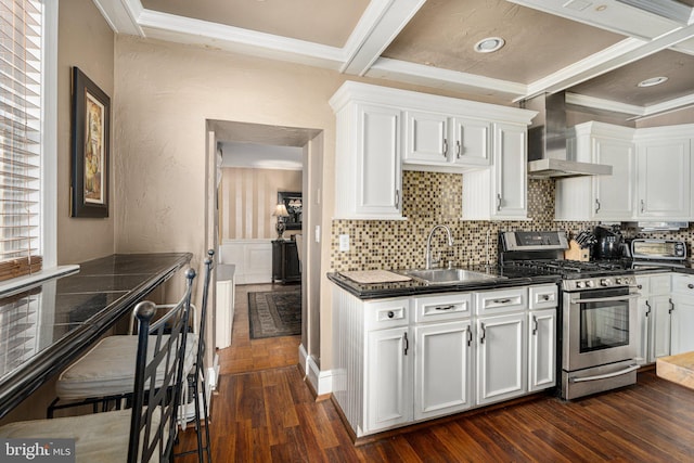 kitchen featuring wall chimney exhaust hood, white cabinetry, sink, and stainless steel gas range