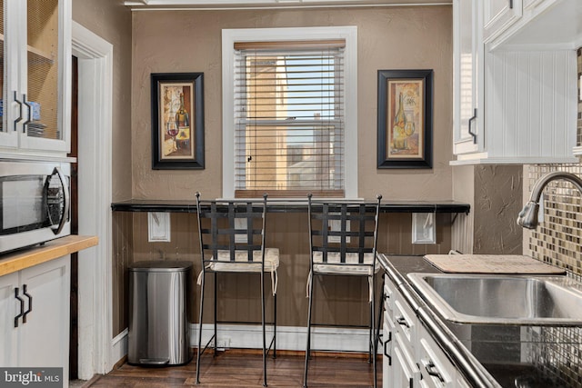 kitchen featuring backsplash, dark hardwood / wood-style flooring, sink, and white cabinets