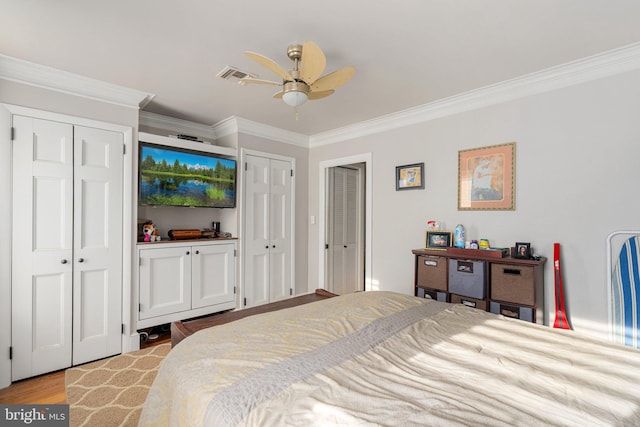 bedroom with multiple closets, ceiling fan, crown molding, and light hardwood / wood-style flooring