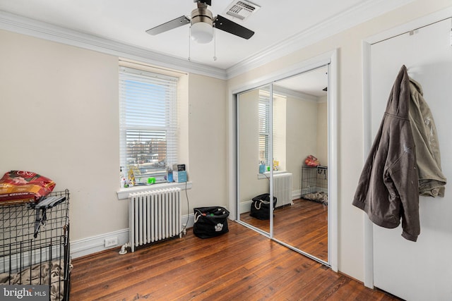 bedroom with ceiling fan, dark hardwood / wood-style flooring, radiator, and a closet